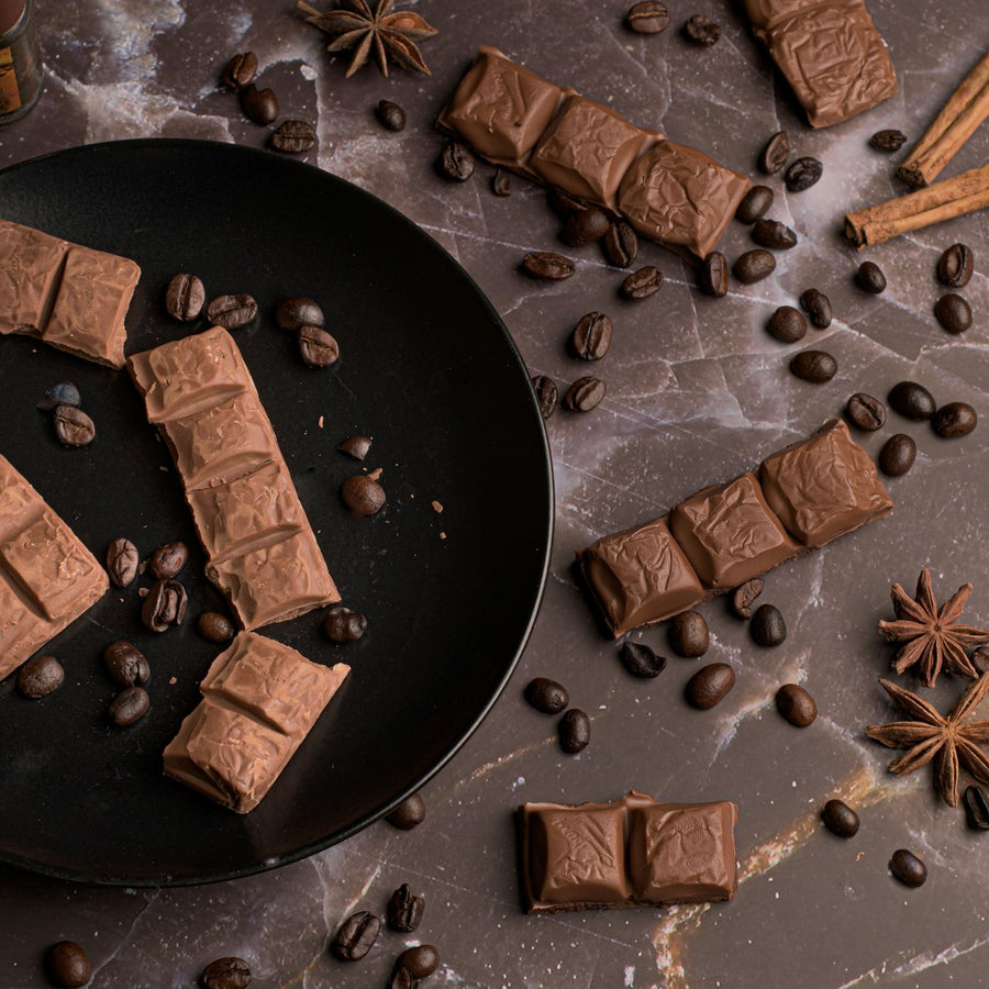 Milk chocolate pieces, coffee beans, cinnamon and star anise on dark marble, gourmand fragrance family